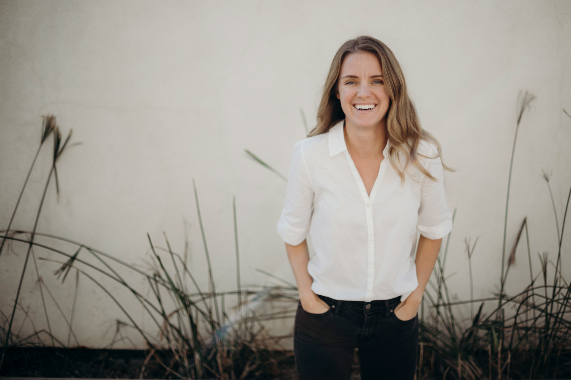 Photo: A white woman smiling with her hands in her pockets.