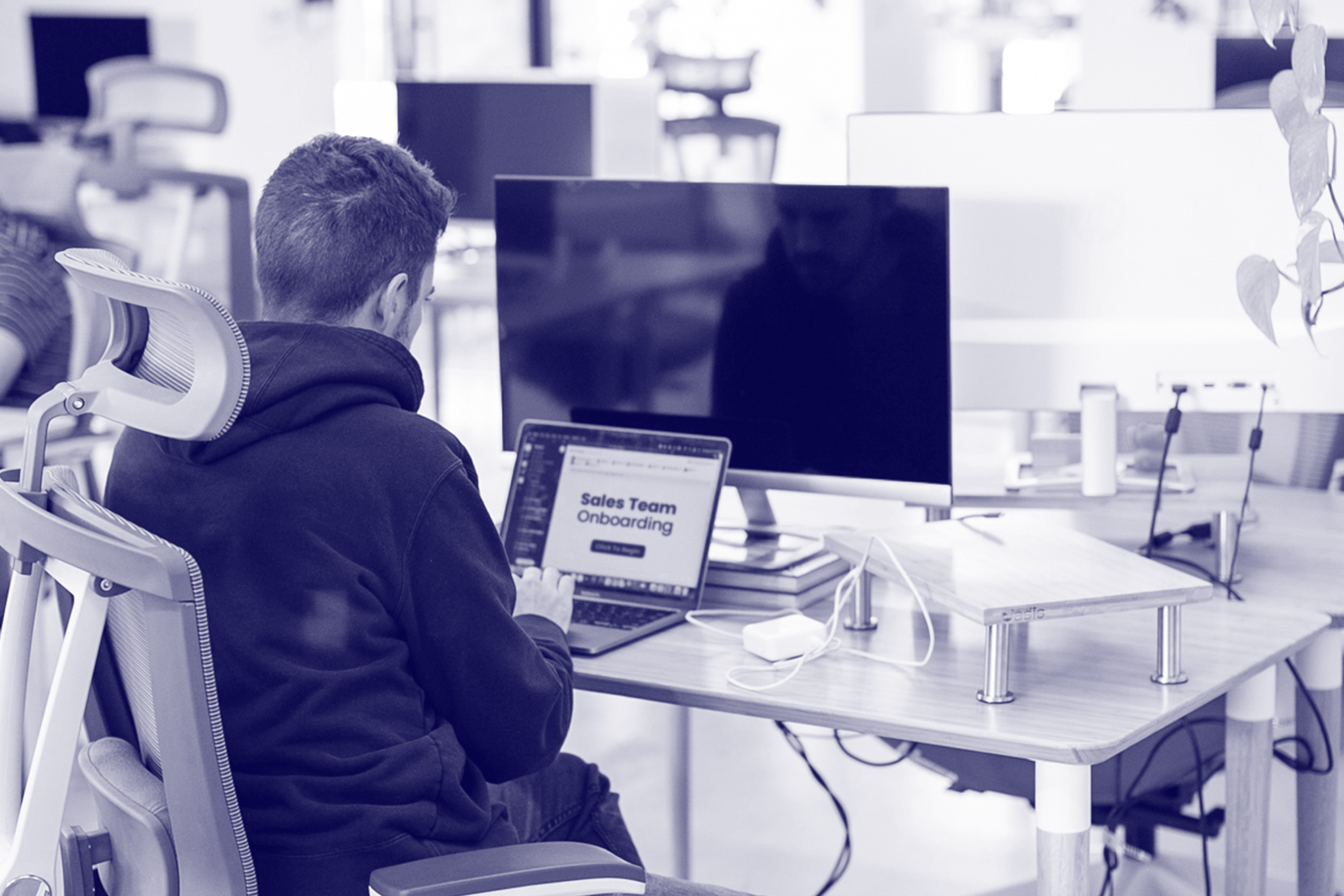 A man sitting at a computer with "Sales Team Onboarding" on the screen.